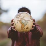 Closeup shot of a male wearing a leather jacket holding a globe in front of him
