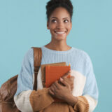Pretty african american student girl with books joyfully looking